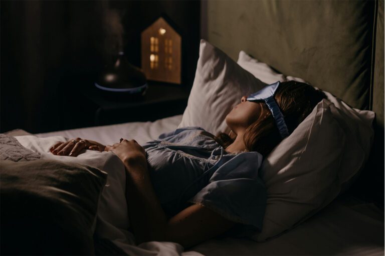 Femme endormie avec un masque de nuit dans une chambre à l'ambiance tamisée