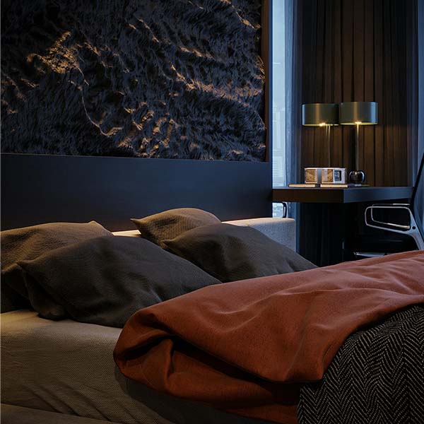 Chambre à coucher moderne avec éclairage tamisé, tête de lit texturée et linge de lit aux tons chauds.