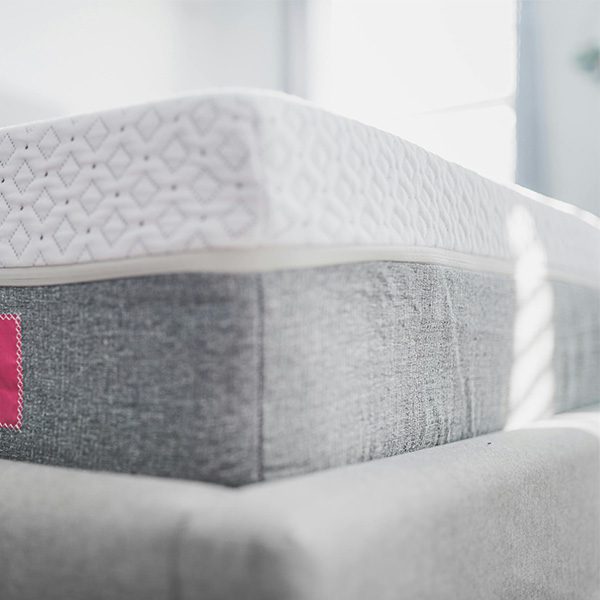 Gros plan d'un matelas moderne avec revêtement blanc à motifs losanges et bordure en tissu gris.