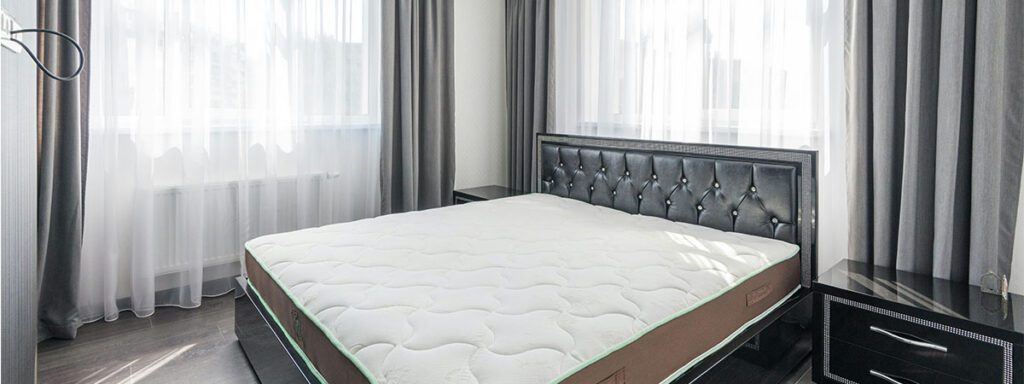 Matelas ergonomique blanc et marron dans une chambre avec rideaux gris