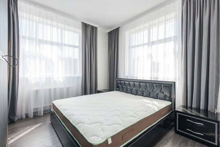 Matelas ergonomique blanc et marron dans une chambre lumineuse avec rideaux gris
